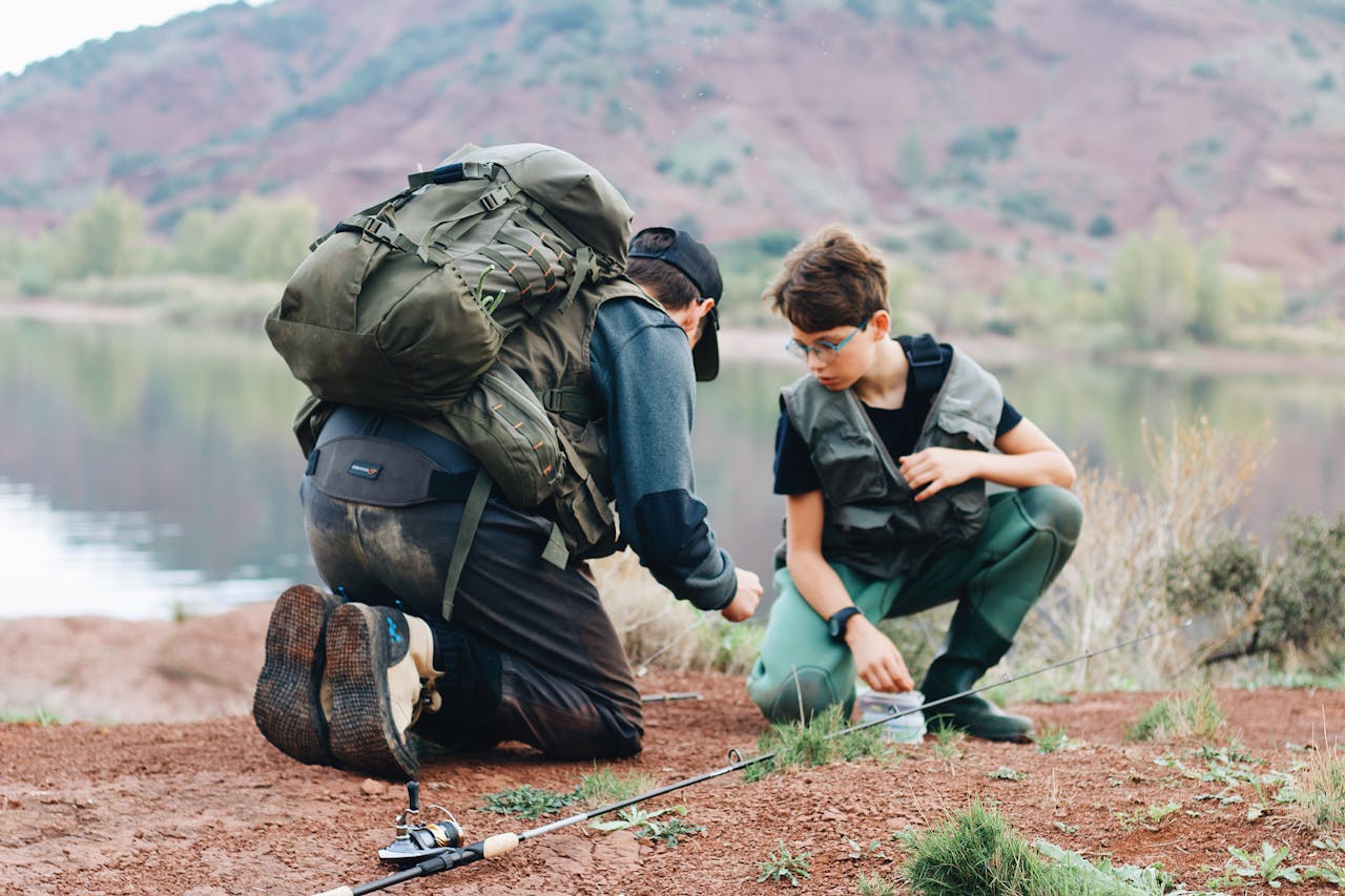 Home Father and son bonding over a fishing trip by a serene lake in an outdoor setting.