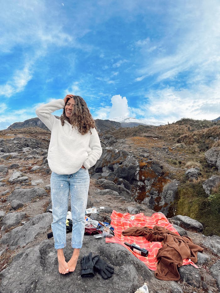 Home Young woman enjoying an outdoor adventure in Caldas, Colombia, surrounded by rocky landscape and blue skies.